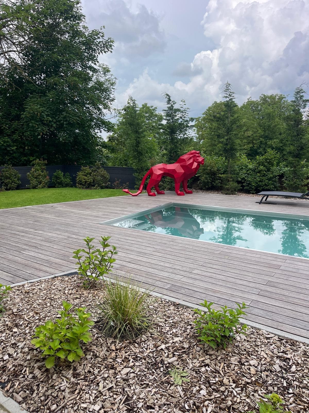 Piscine extérieure habillée de pierre dans un jardin paysager