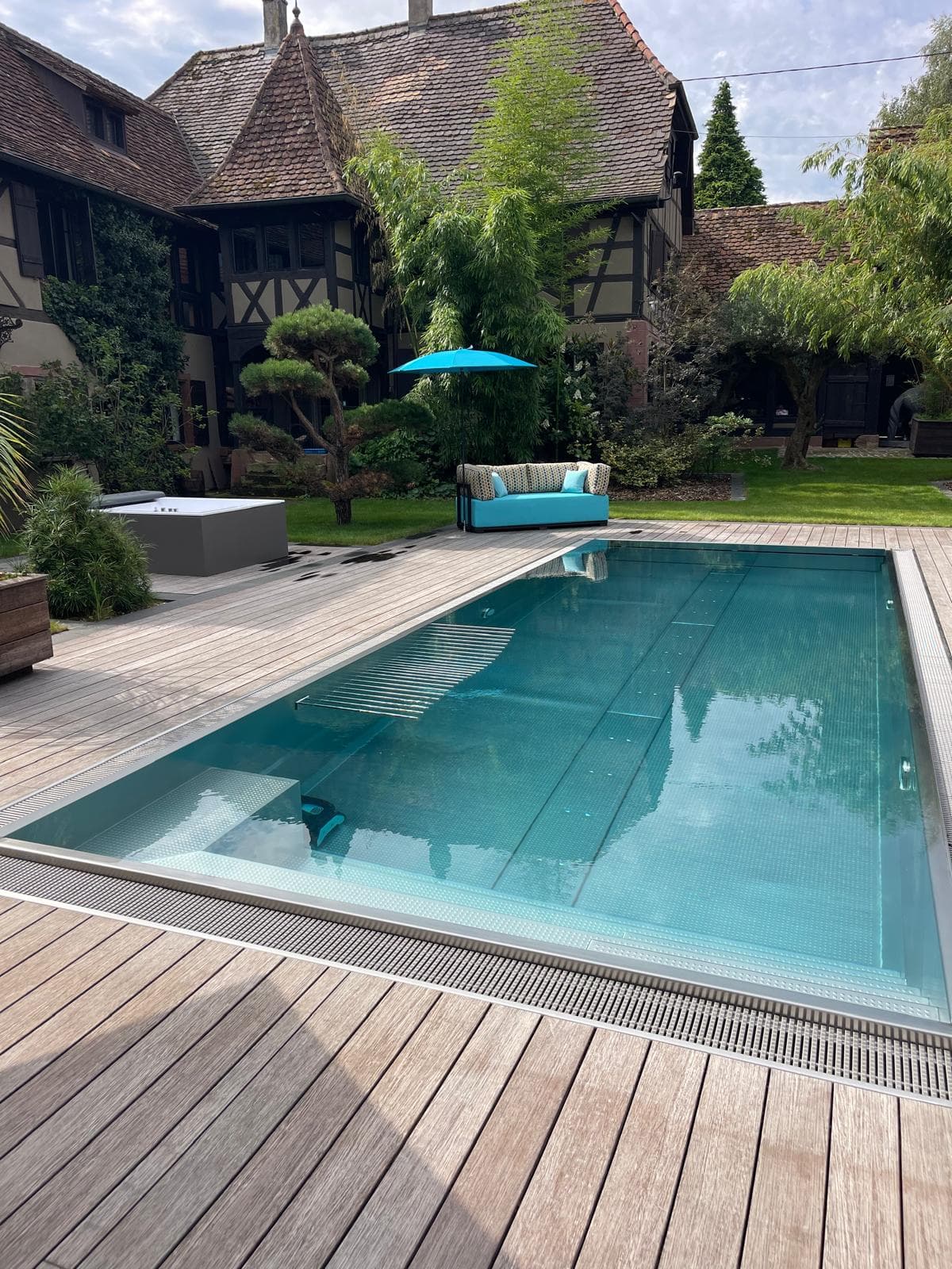 Piscine avec écran de bambous et maison alsacienne en fond