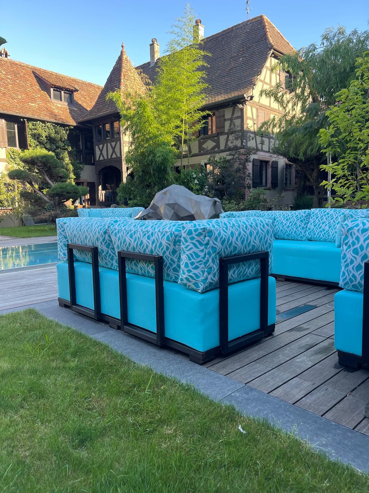 Salon outdoor avec mobilier turquoise au bord d'une piscine