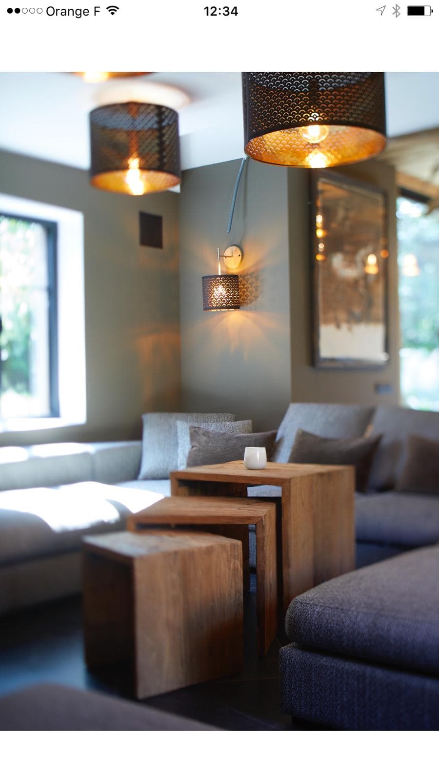 Coin lounge avec suspensions noires perforées et canapé gris